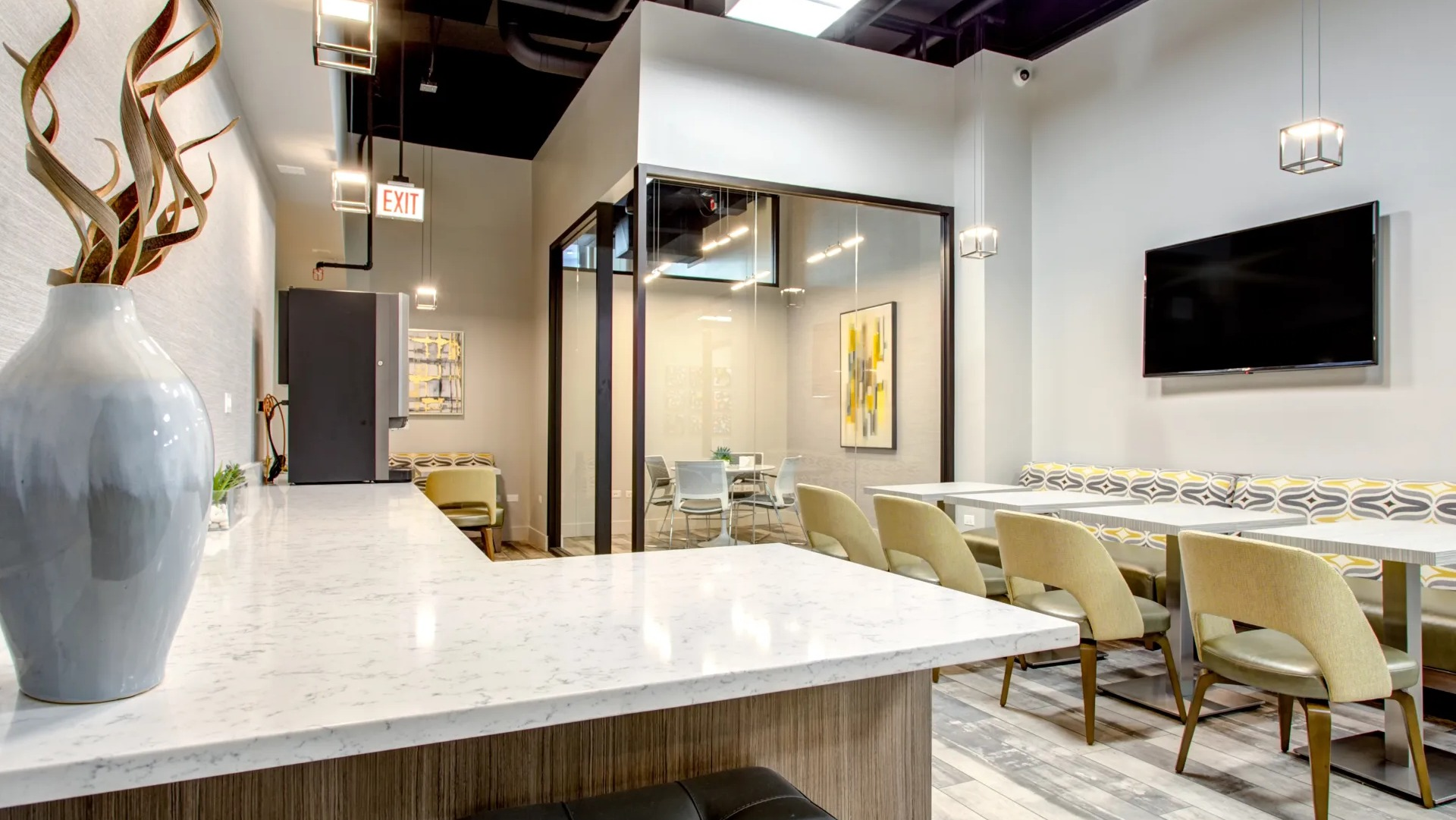 Community cafe lounge with banquette seating, TV and tables for coworking or gatherings at 180 North Jefferson apartments in Chicago