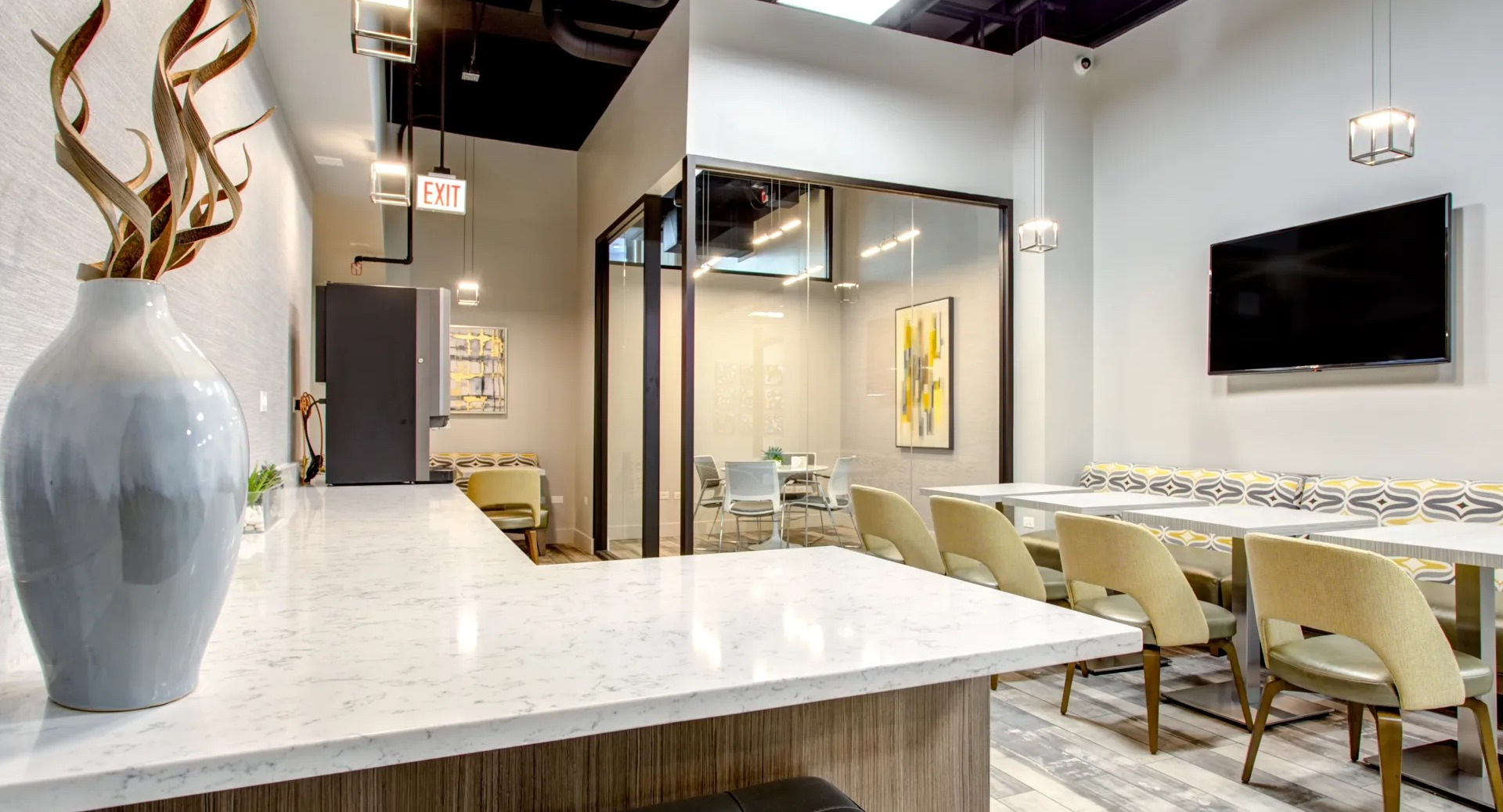 Community cafe lounge with banquette seating, TV and tables for coworking or gatherings at 180 North Jefferson apartments in Chicago