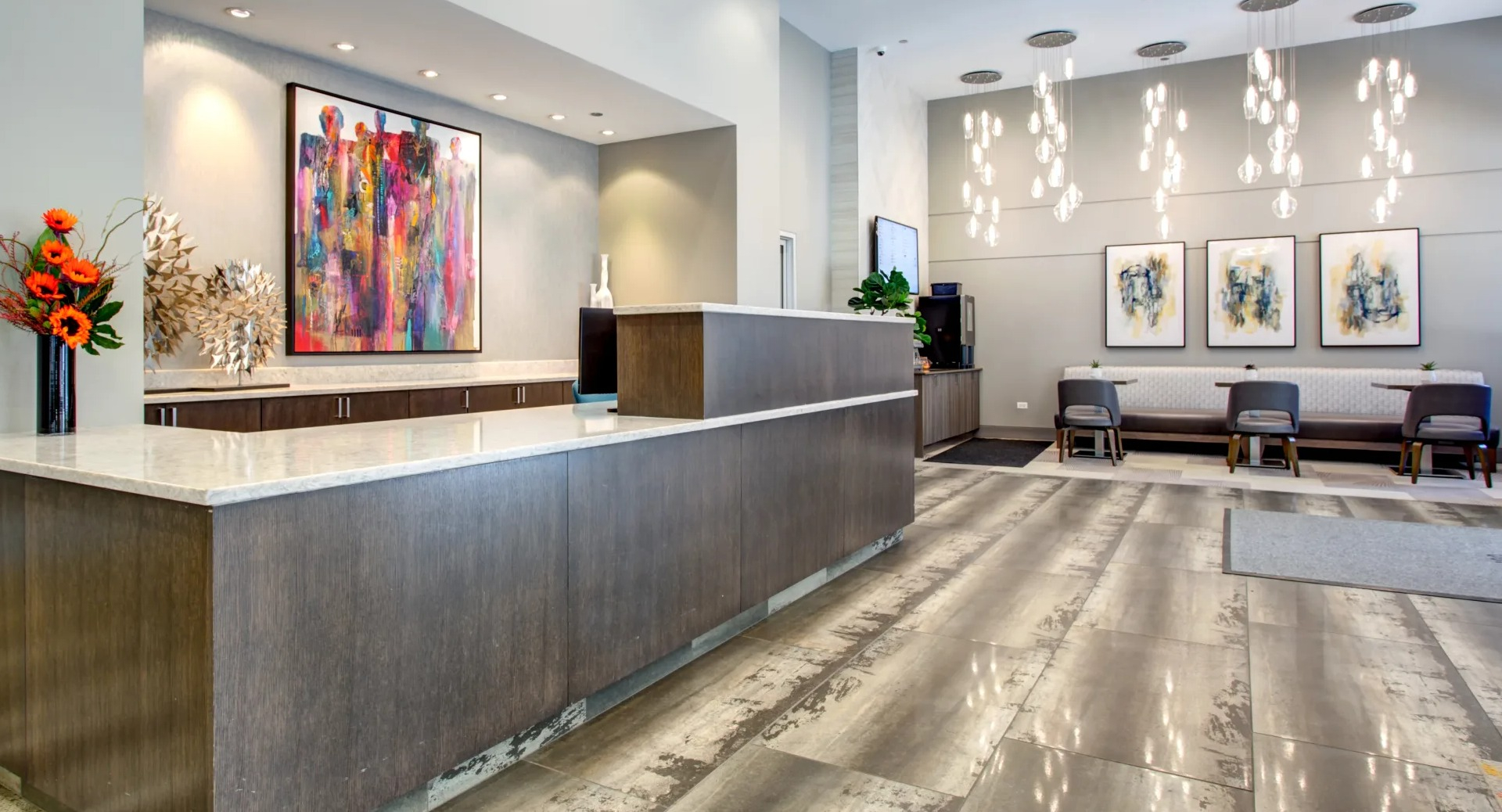 Hotel-style lobby with concierge desk, modern art and statement lighting offering a welcoming arrival at 180 North Jefferson apartments in Chicago