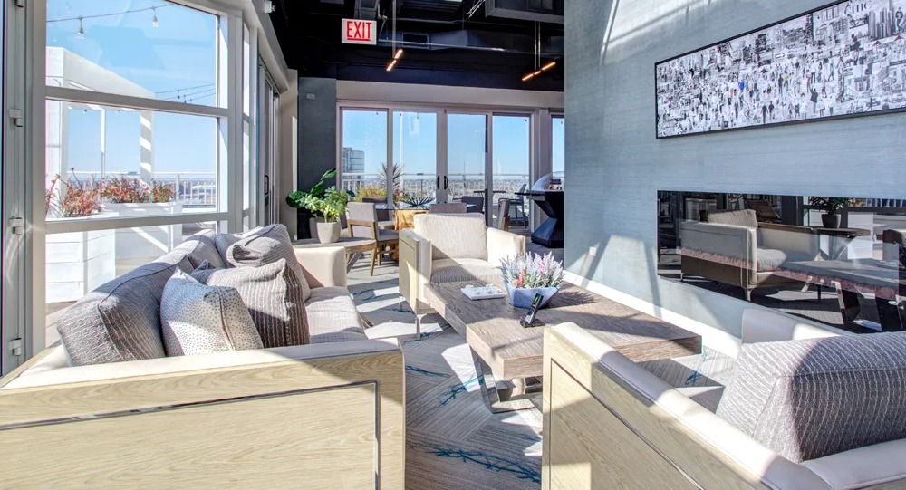 Indoor rooftop lounge with large windows, modern seating, statement lighting and a fireplace at 180 North Jefferson apartments in Chicago