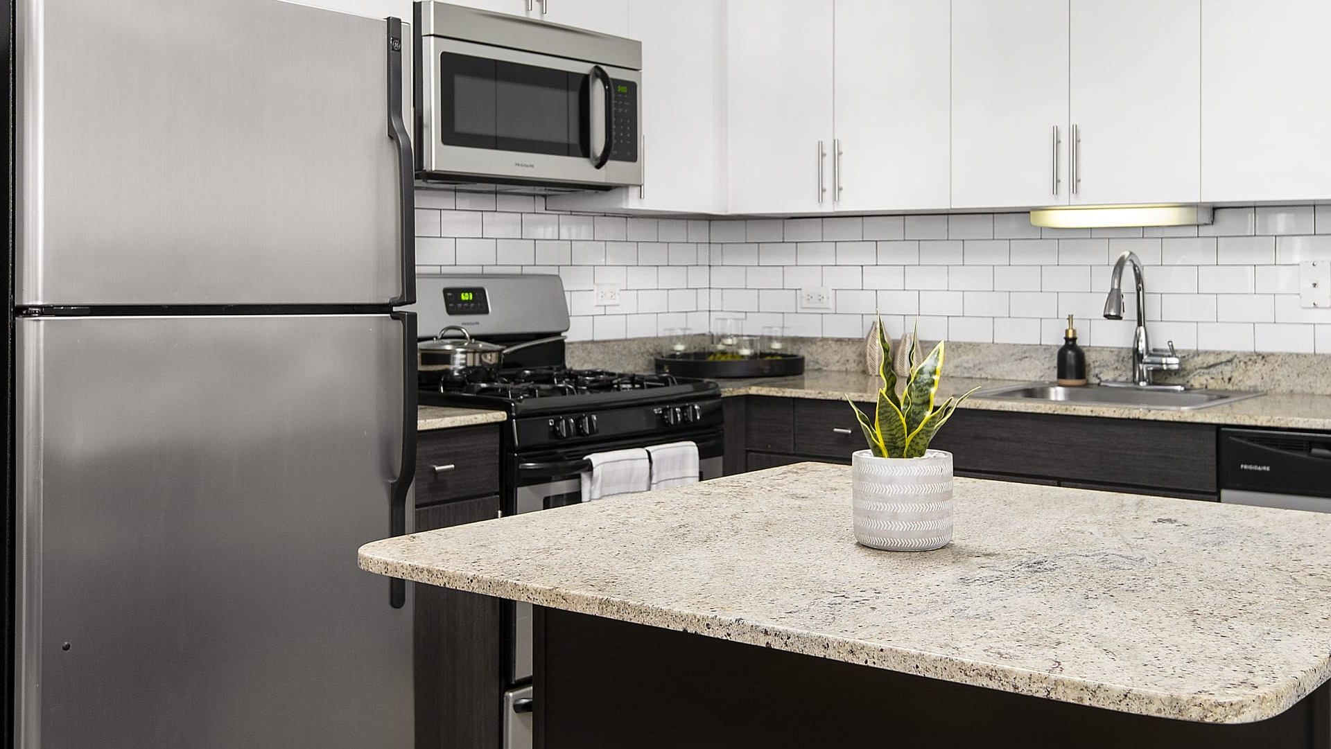 Modern kitchen with stainless steel appliances, subway tile backsplash, island seating and cabinets at 180 North Jefferson apartments in Chicago
