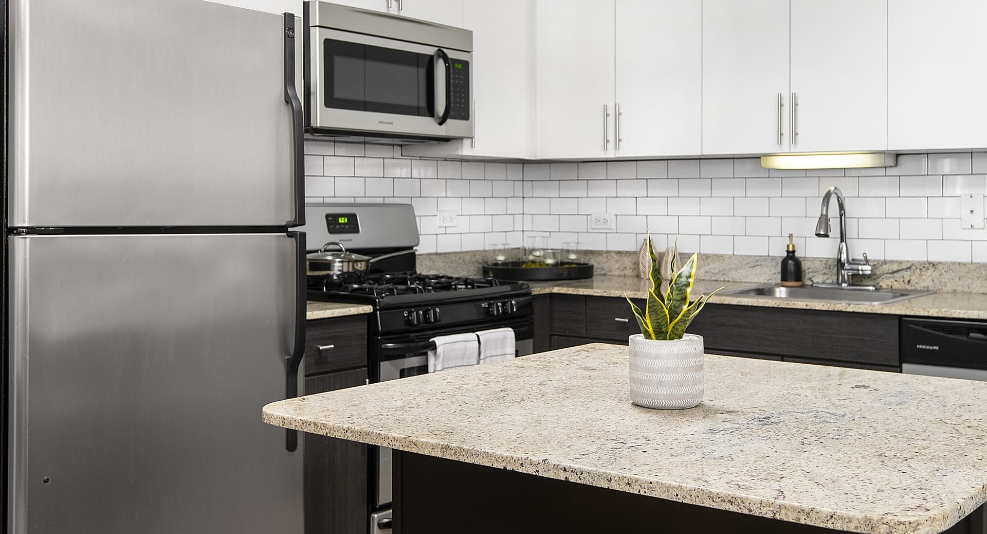 Modern kitchen with stainless steel appliances, subway tile backsplash, island seating and cabinets at 180 North Jefferson apartments in Chicago
