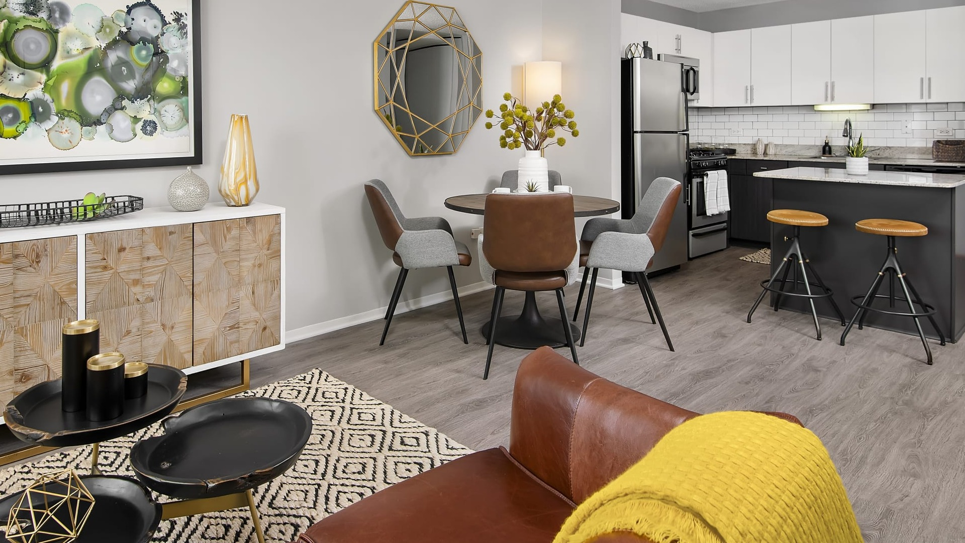 Open layout connecting living room, dining table and kitchen island with bar stools and modern finishes at 180 North Jefferson apartments in Chicago