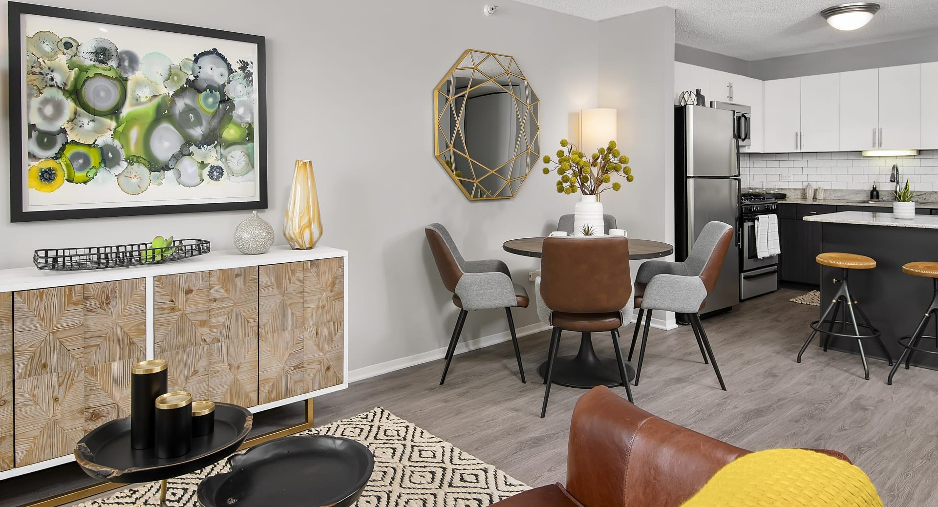 Open layout connecting living room, dining table and kitchen island with bar stools and modern finishes at 180 North Jefferson apartments in Chicago