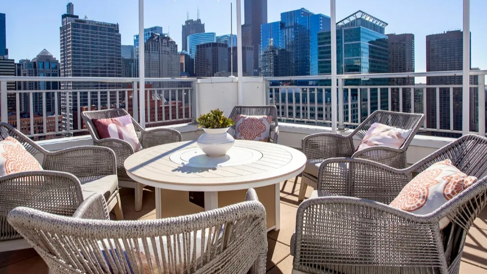 Rooftop lounge seating with round table, woven chairs and skyline views under bistro lights at 180 North Jefferson apartments in Chicago