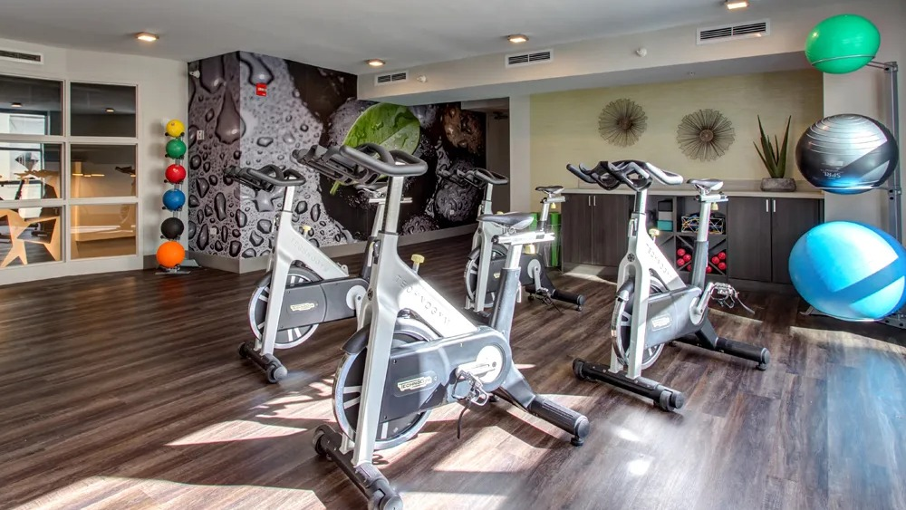 Bright spin and yoga studio with stationary bikes, mirrored wall and workout accessories at 180 North Jefferson apartments in Chicago