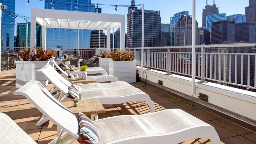 Rooftop sundeck with chaise lounges, pergola shade and sweeping downtown skyline views at 180 North Jefferson apartments in Chicago