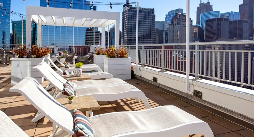 Rooftop sundeck with chaise lounges, pergola shade and sweeping downtown skyline views at 180 North Jefferson apartments in Chicago