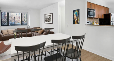 Open-concept living and dining area with large windows, hardwood floors, and a breakfast bar by the kitchen at 20 E Scott apartments in Chicago