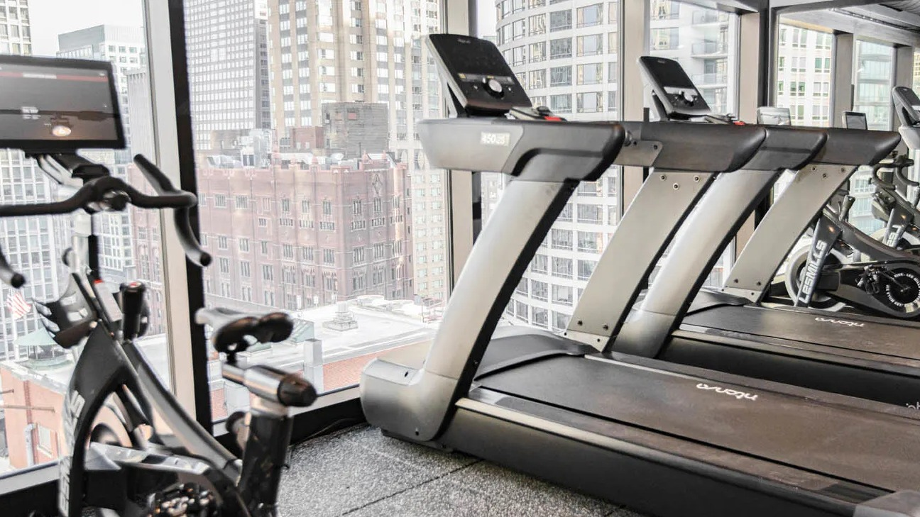 Fitness center featuring treadmills facing skyline windows for energizing cardio workouts at 21 E Chestnut apartments in downtown Chicago