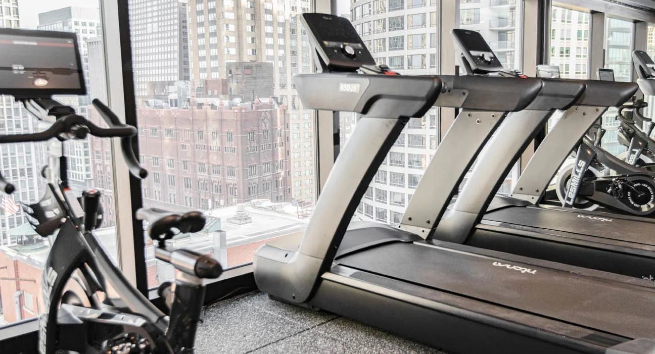 Fitness center featuring treadmills facing skyline windows for energizing cardio workouts at 21 E Chestnut apartments in downtown Chicago