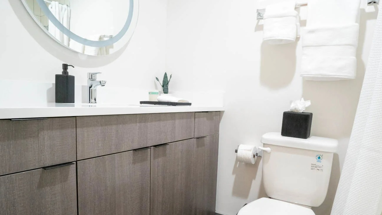 Modern bathroom with white quartz countertop, sleek chrome faucet, gray wood vanity, and fresh towels at 21 E Chestnut apartments in Chicago
