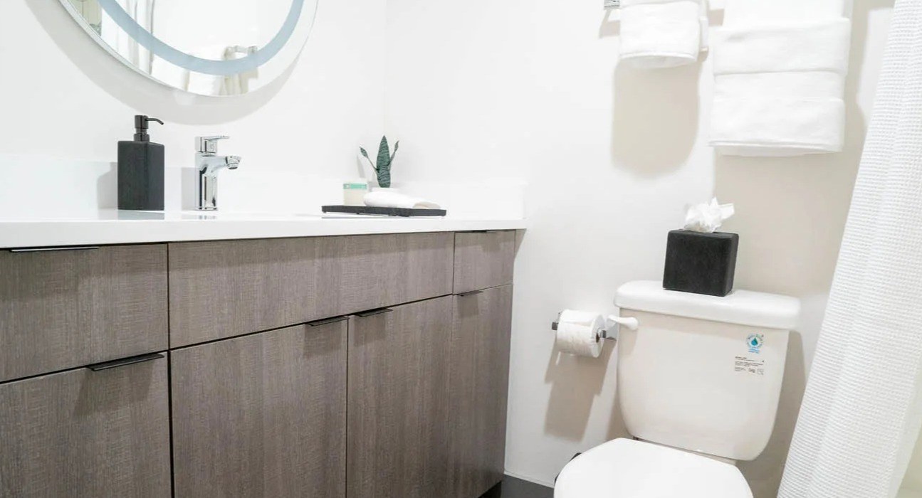 Modern bathroom with white quartz countertop, sleek chrome faucet, gray wood vanity, and fresh towels at 21 E Chestnut apartments in Chicago