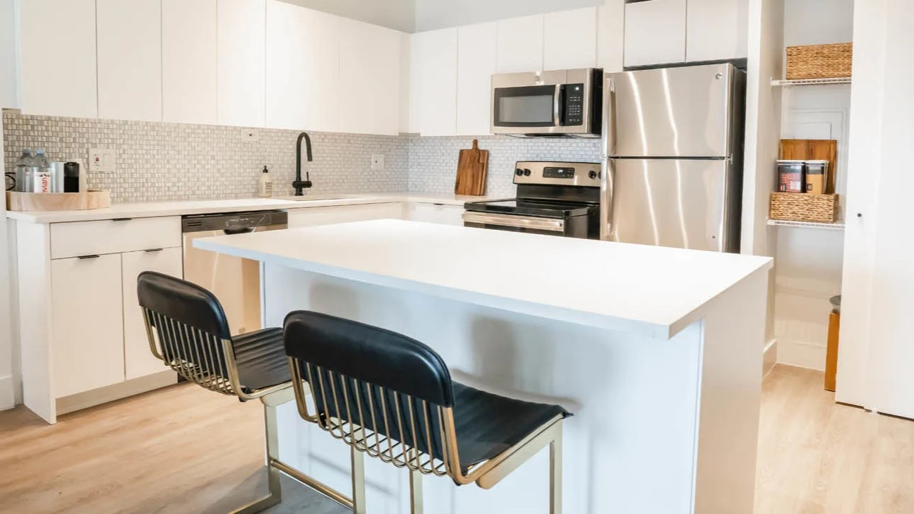 Modern kitchen with white cabinets, island seating, tile backsplash, and stainless steel appliances at 21 E Chestnut apartments in Chicago