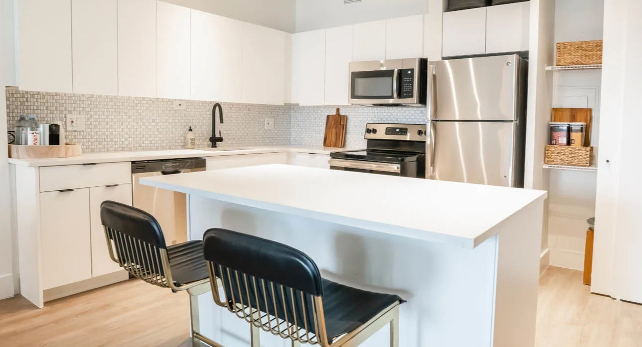 Modern kitchen with white cabinets, island seating, tile backsplash, and stainless steel appliances at 21 E Chestnut apartments in Chicago