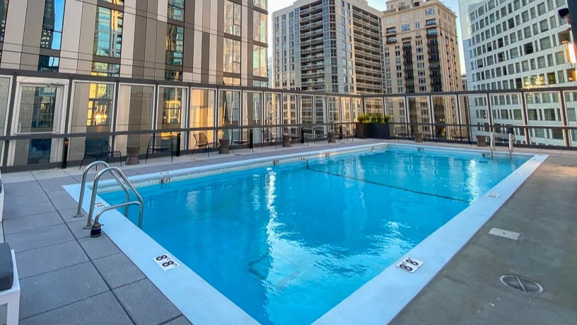 Rooftop swimming pool with lap lanes, deck chairs, and panoramic skyline views at 21 E Chestnut apartments in Chicago