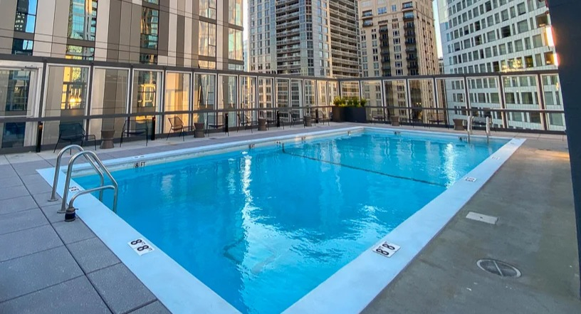Rooftop swimming pool with lap lanes, deck chairs, and panoramic skyline views at 21 E Chestnut apartments in Chicago