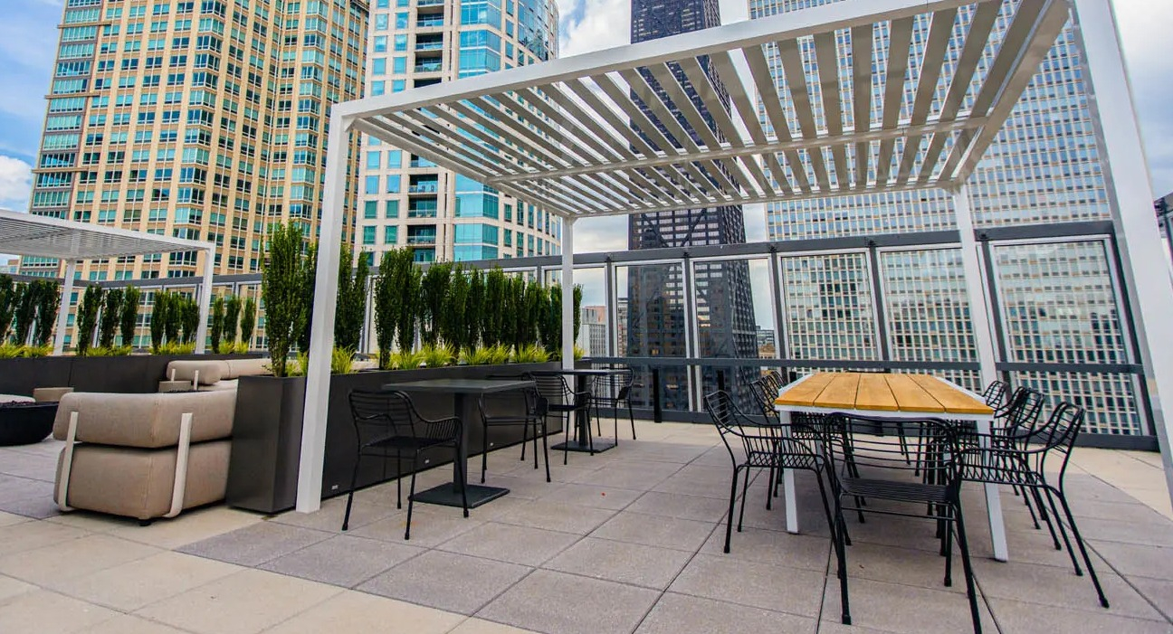 Skyline terrace with pergola shade, outdoor tables, and long communal dining area at 21 E Chestnut apartments in Chicago