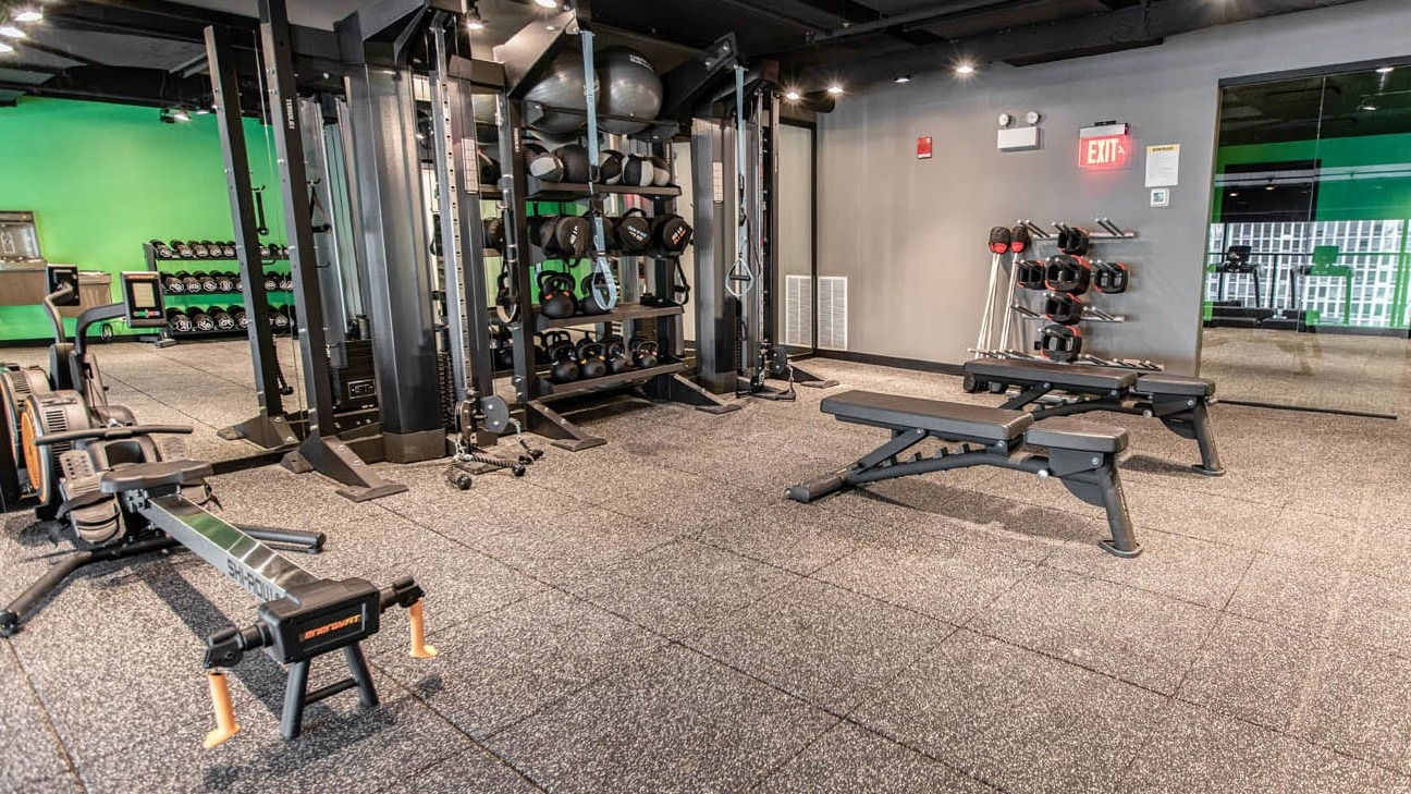 Spacious gym with benches, rowing machine, cable stations, and mirrored wall for full-body training at 21 E Chestnut apartments in Chicago