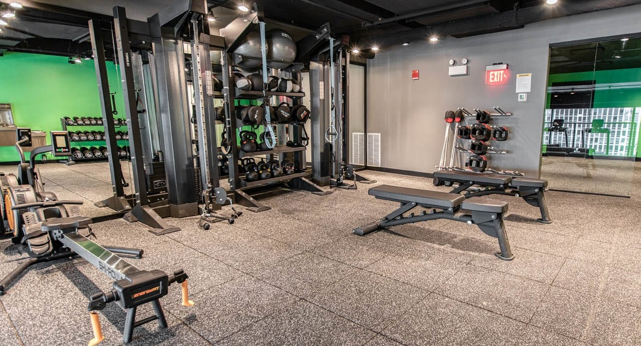 Spacious gym with benches, rowing machine, cable stations, and mirrored wall for full-body training at 21 E Chestnut apartments in Chicago