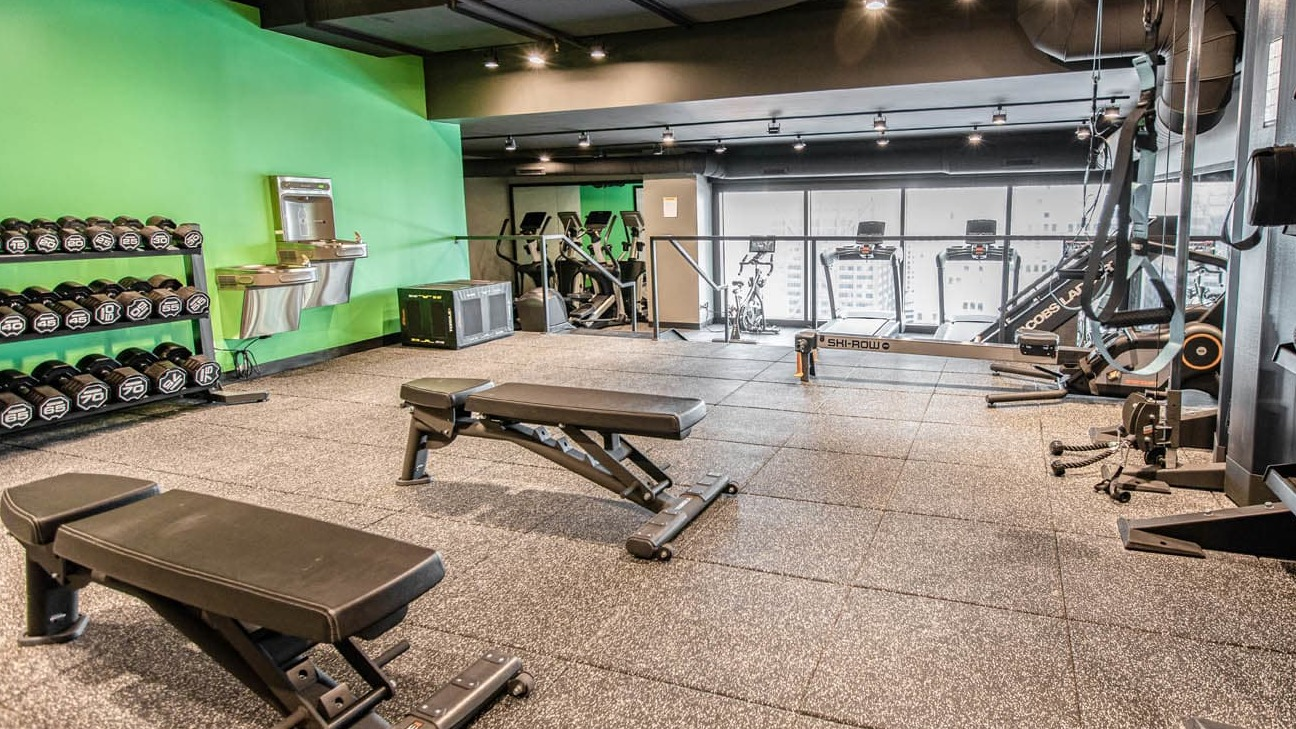 Strength training room with free weights, kettlebells, benches, and TRX setup at 21 E Chestnut apartments in Chicago