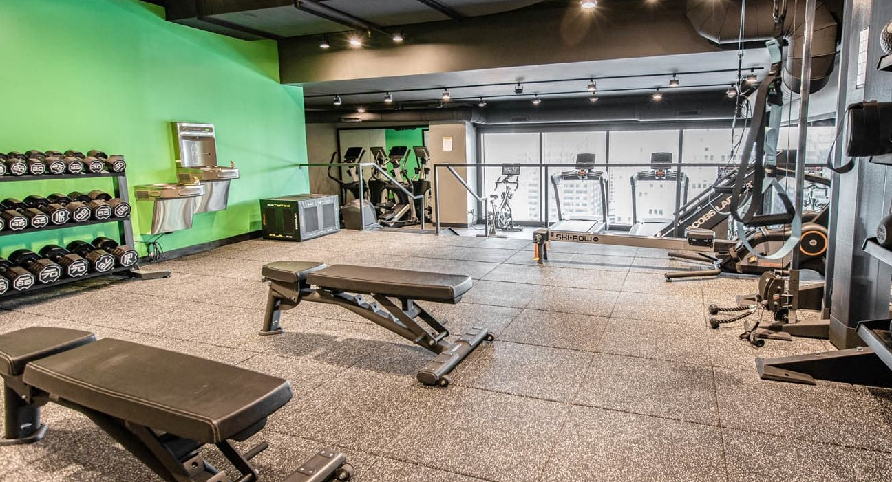Strength training room with free weights, kettlebells, benches, and TRX setup at 21 E Chestnut apartments in Chicago