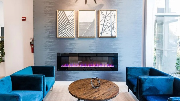 Contemporary lobby with a sputnik chandelier, linear fireplace, and blue velvet lounge chairs at 2101 South Michigan Apartments in Chicago