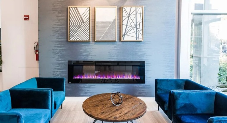 Contemporary lobby with a sputnik chandelier, linear fireplace, and blue velvet lounge chairs at 2101 South Michigan Apartments in Chicago