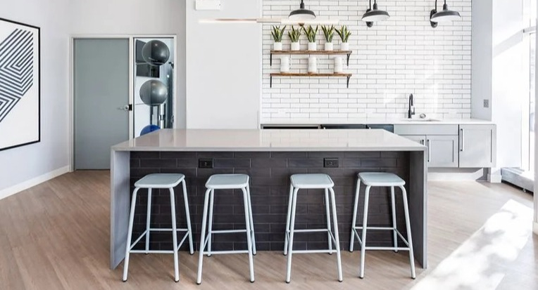 Resident social kitchen with a large island, bar stools, and a white subway tile backsplash under industrial lights at 2101 South Michigan Apartments in Chicago