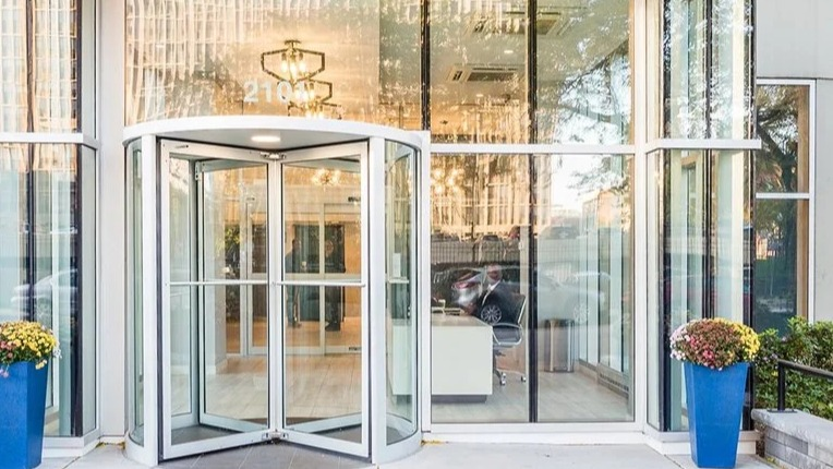 Welcoming lobby entrance with a glass revolving door, contemporary canopy, and planters at 2101 South Michigan Apartments in Chicago, creating a polished first impression