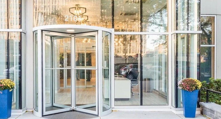 Welcoming lobby entrance with a glass revolving door, contemporary canopy, and planters at 2101 South Michigan Apartments in Chicago, creating a polished first impression