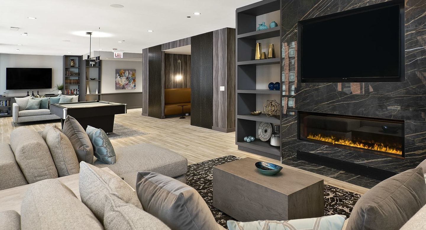 Upscale club lounge at 215 West Chicago featuring modern sofas, built-in shelves, a linear fireplace, and a large TV for relaxing