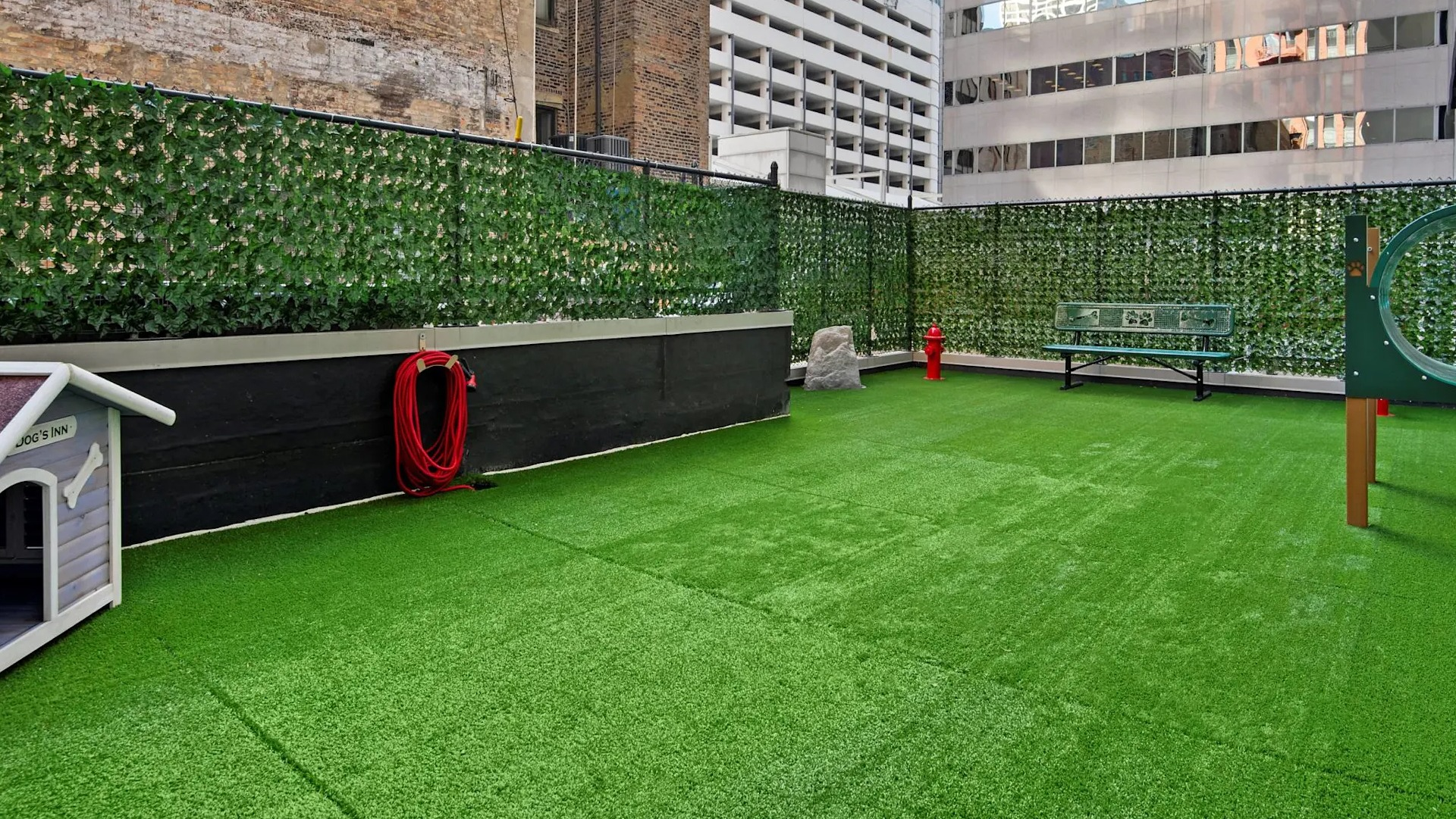 Pet-friendly dog run at 215 West in Chicago with turf, a doghouse, agility tunnel, and seating, offering convenient on-site space for play and exercise