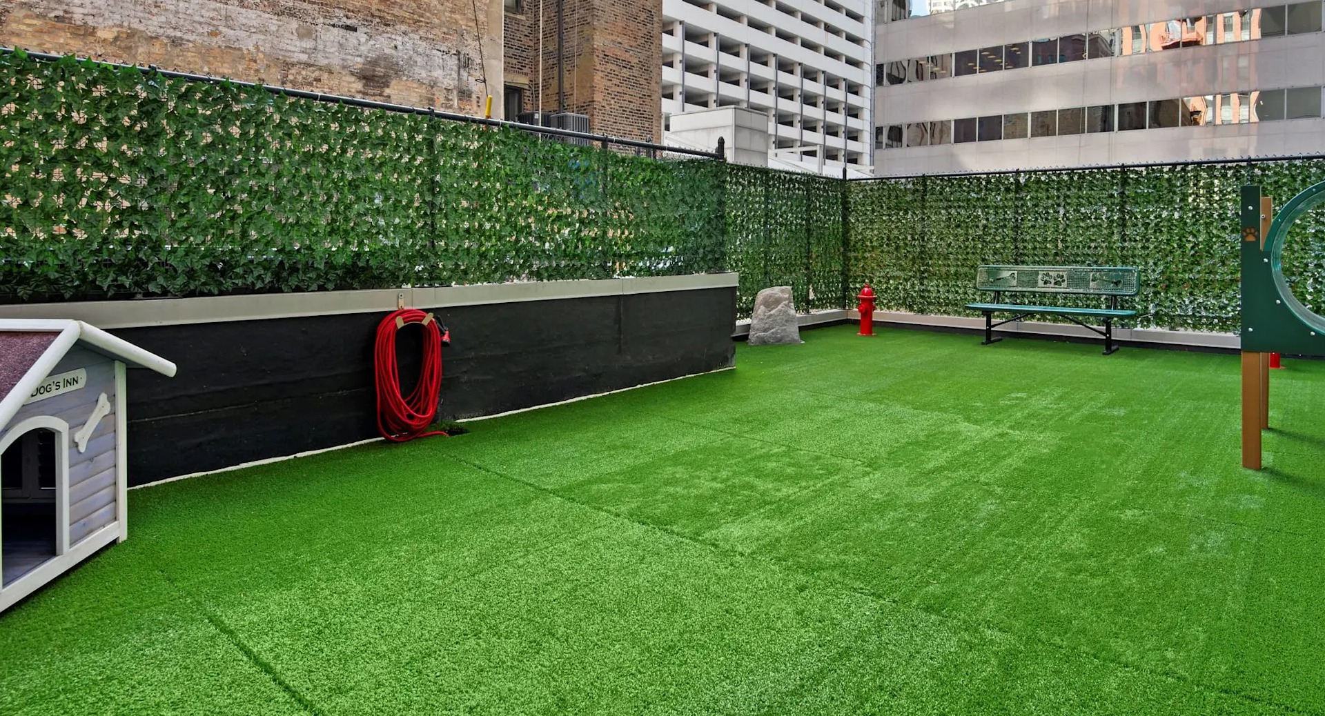 Pet-friendly dog run at 215 West in Chicago with turf, a doghouse, agility tunnel, and seating, offering convenient on-site space for play and exercise