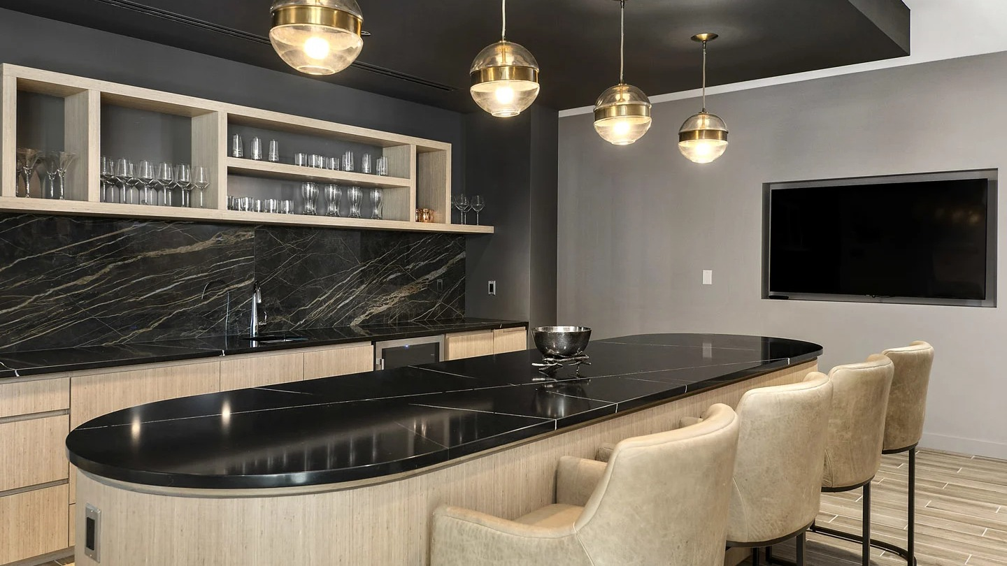 Entertainer’s kitchen at 215 West apartments in Chicago, showcasing a curved island, black stone counters, and globe pendants with bar seating