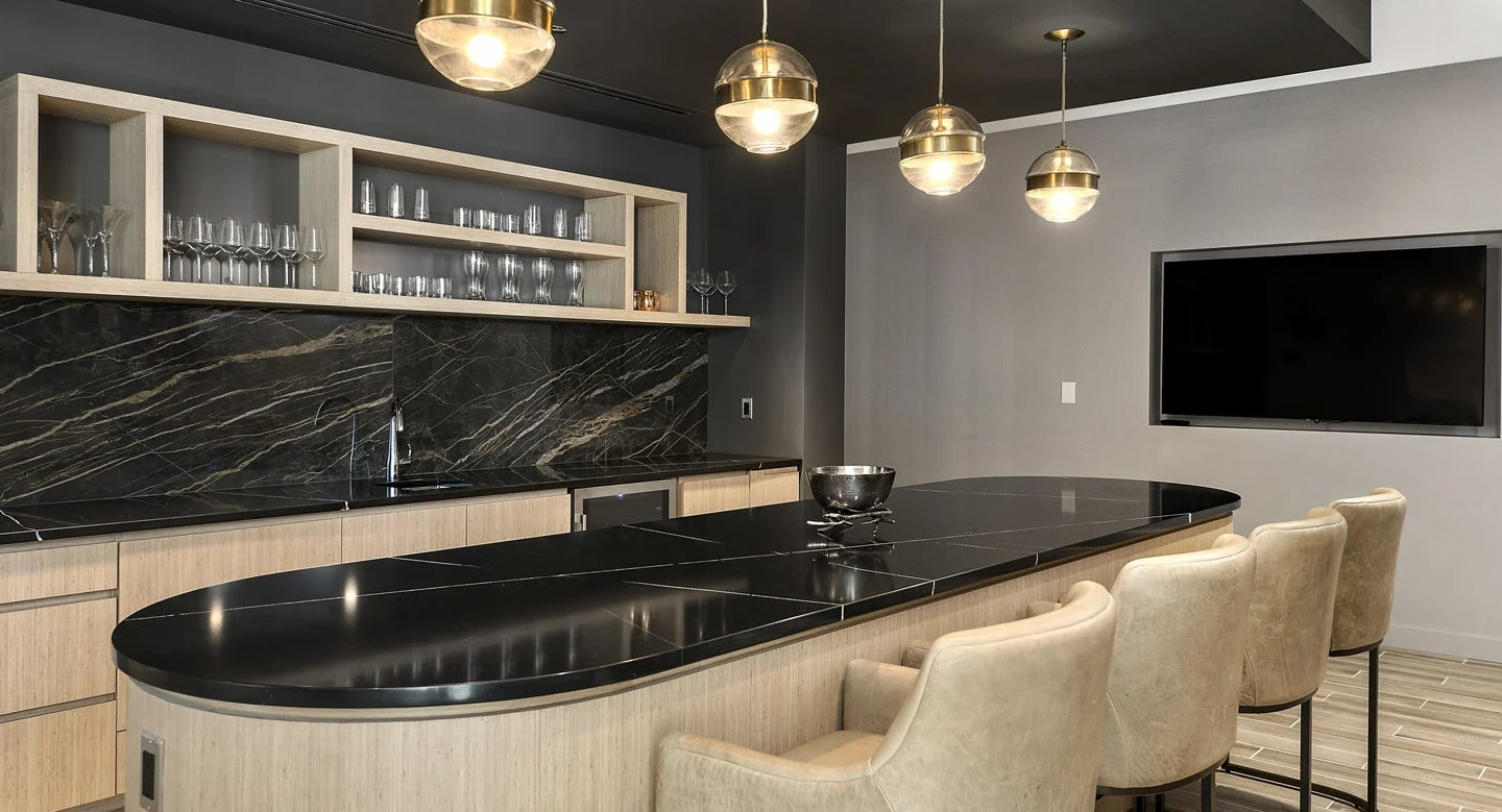 Entertainer’s kitchen at 215 West apartments in Chicago, showcasing a curved island, black stone counters, and globe pendants with bar seating