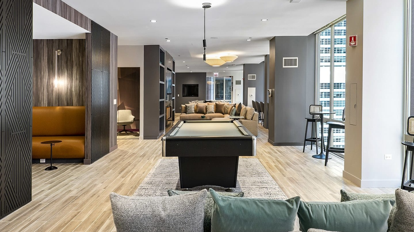 Spacious game lounge at 215 West in Chicago with a pool table, multiple seating zones, tall windows, and modern finishes for resident hangouts