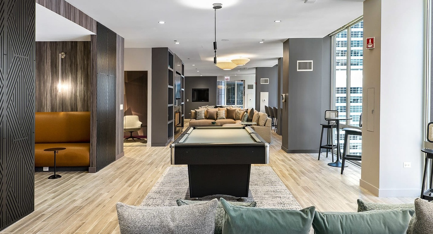 Spacious game lounge at 215 West in Chicago with a pool table, multiple seating zones, tall windows, and modern finishes for resident hangouts