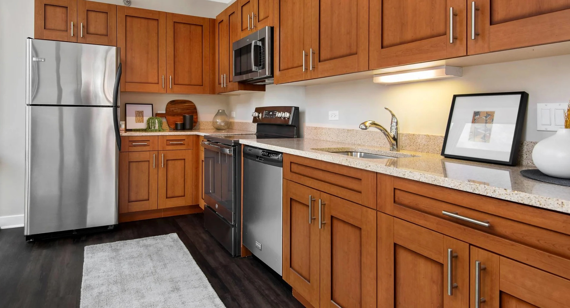 Galley kitchen at 215 West Chicago with stainless appliances, abundant wood cabinetry, stone counters, and a tall window bringing in downtown views and light