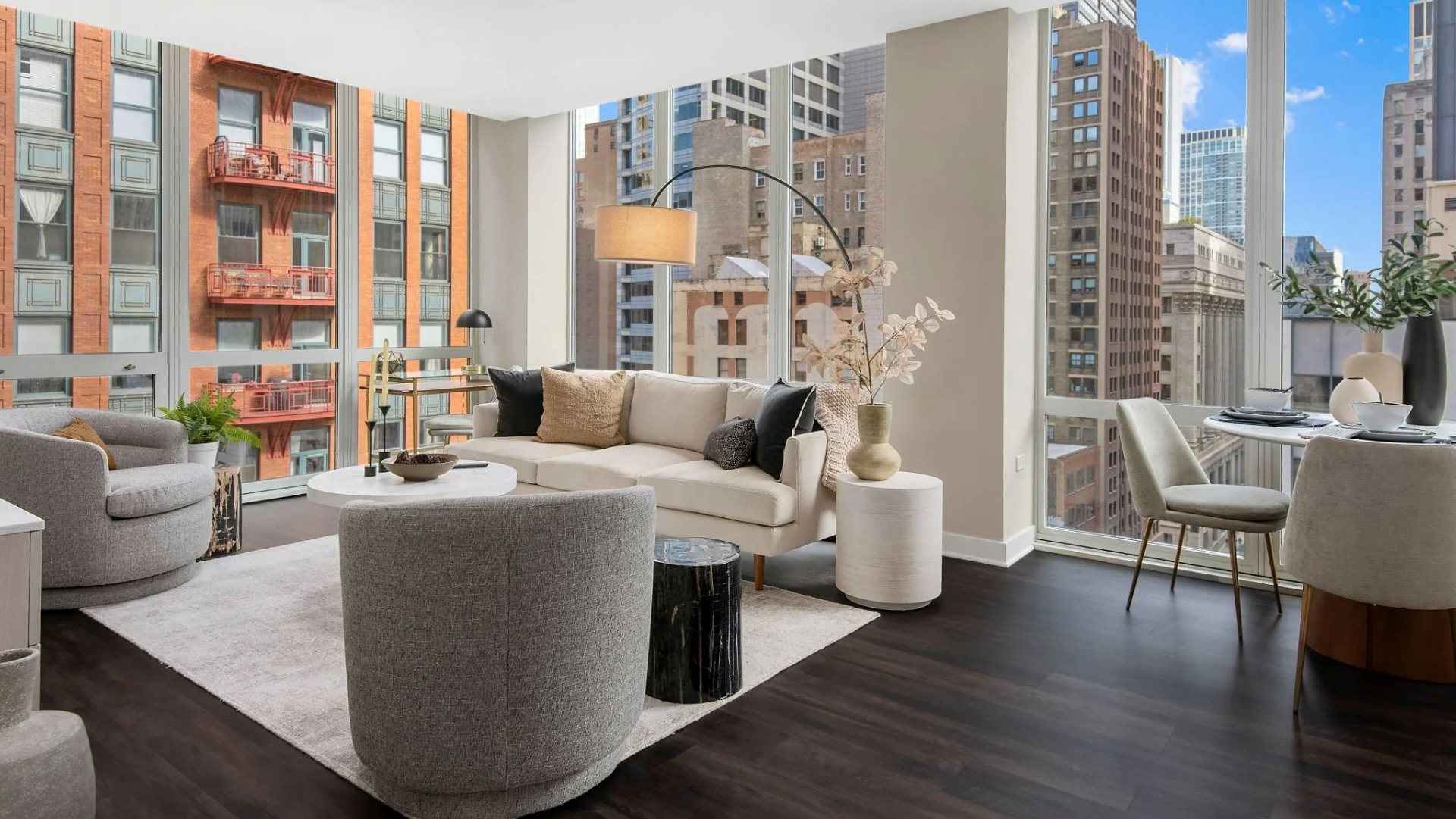 Corner living and dining area at 215 West apartments in Chicago, styled with modern furniture, dark floors, and dramatic floor-to-ceiling city views