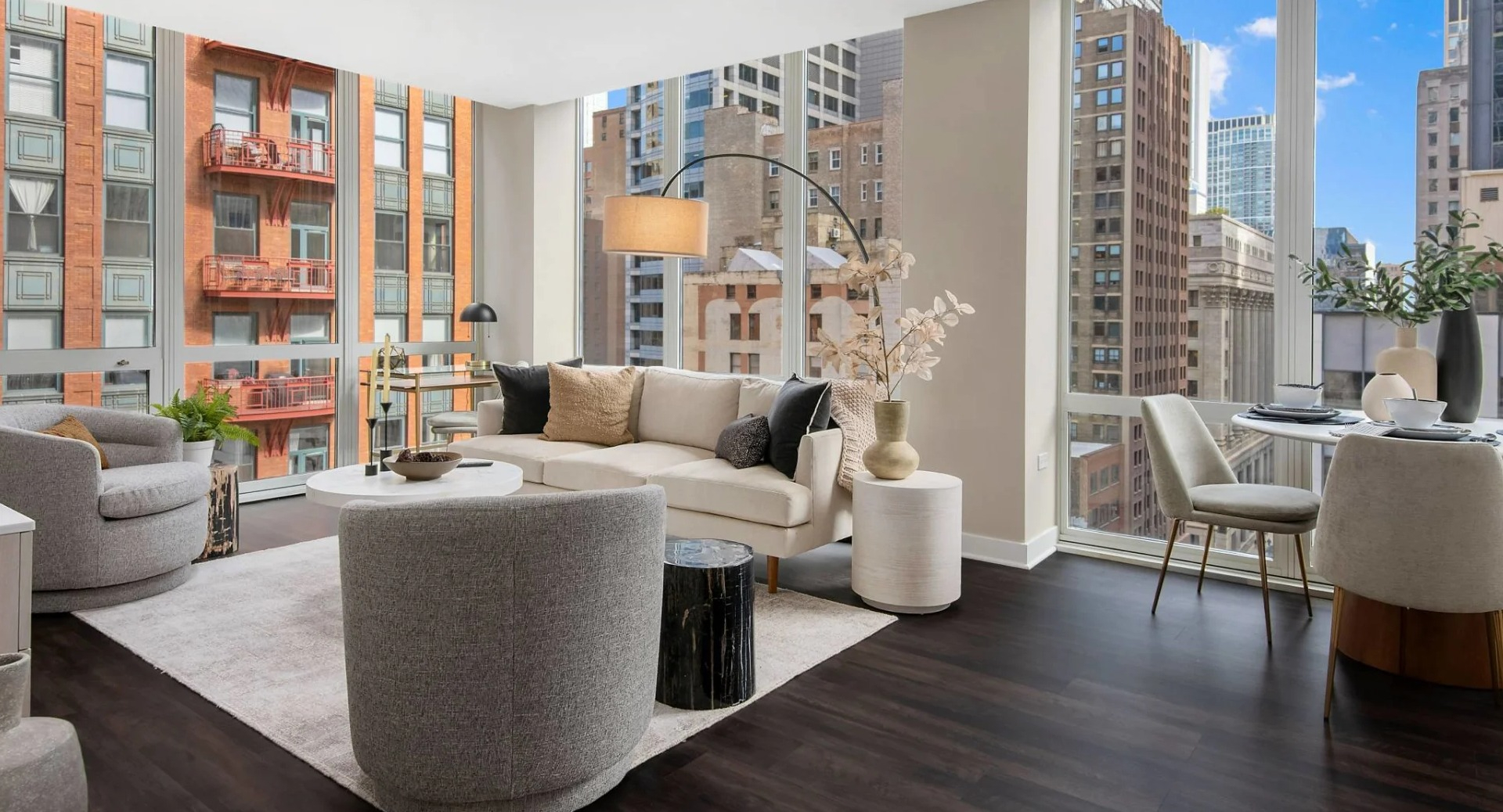 Corner living and dining area at 215 West apartments in Chicago, styled with modern furniture, dark floors, and dramatic floor-to-ceiling city views