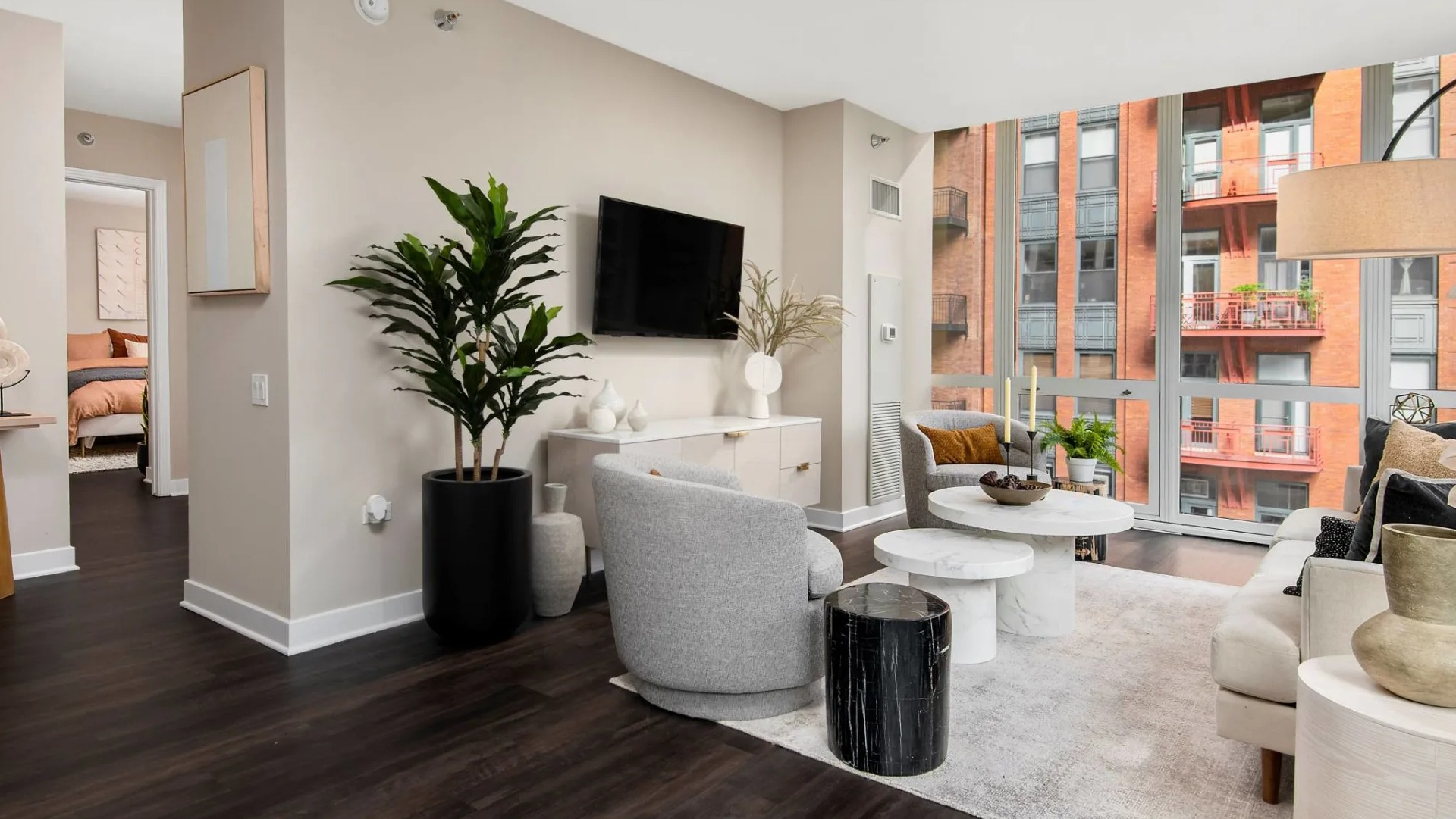 Open living room layout at 215 West Chicago with modern seating, layered coffee tables, tall indoor plant, and expansive windows facing the skyline