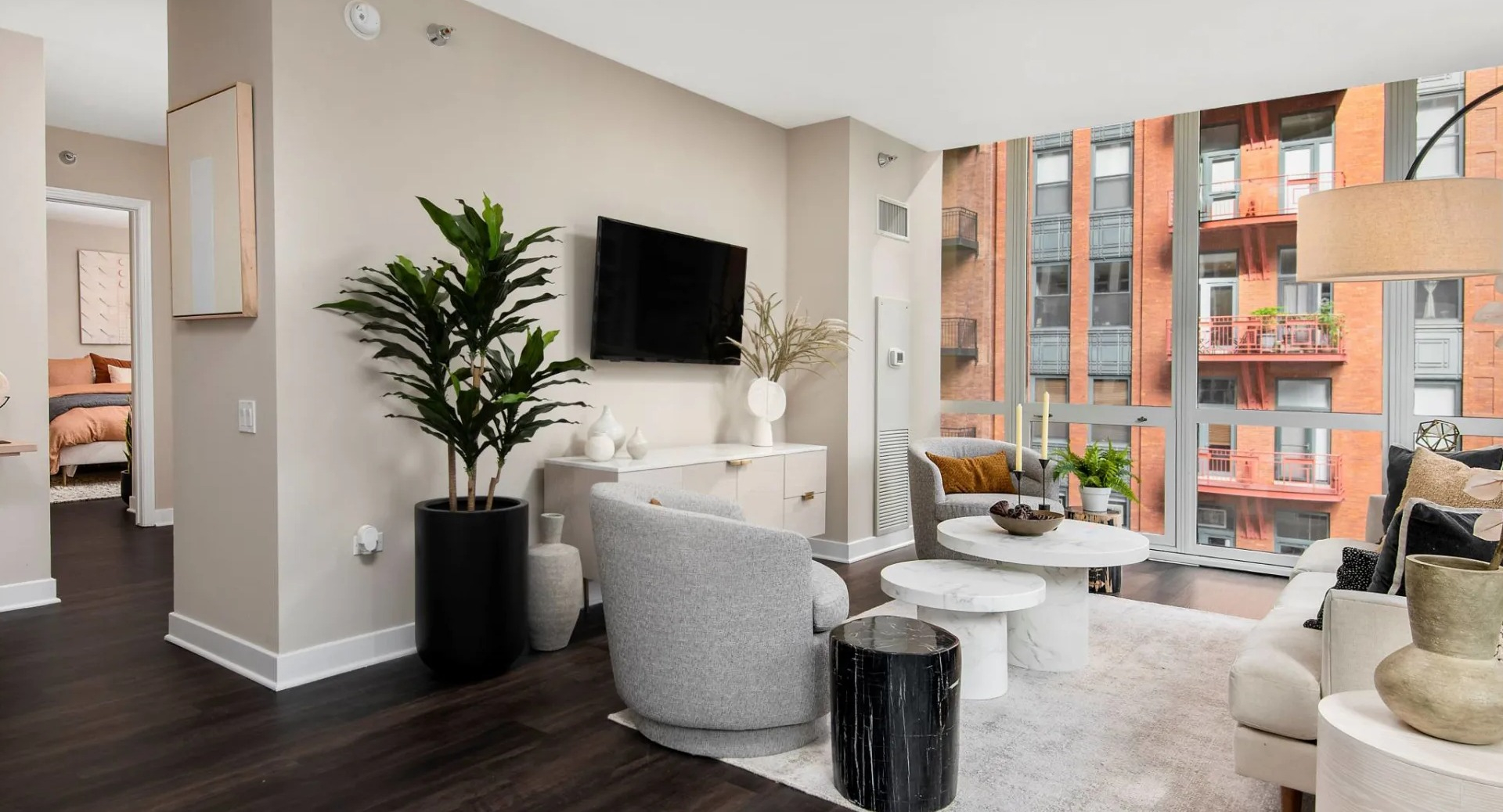 Open living room layout at 215 West Chicago with modern seating, layered coffee tables, tall indoor plant, and expansive windows facing the skyline