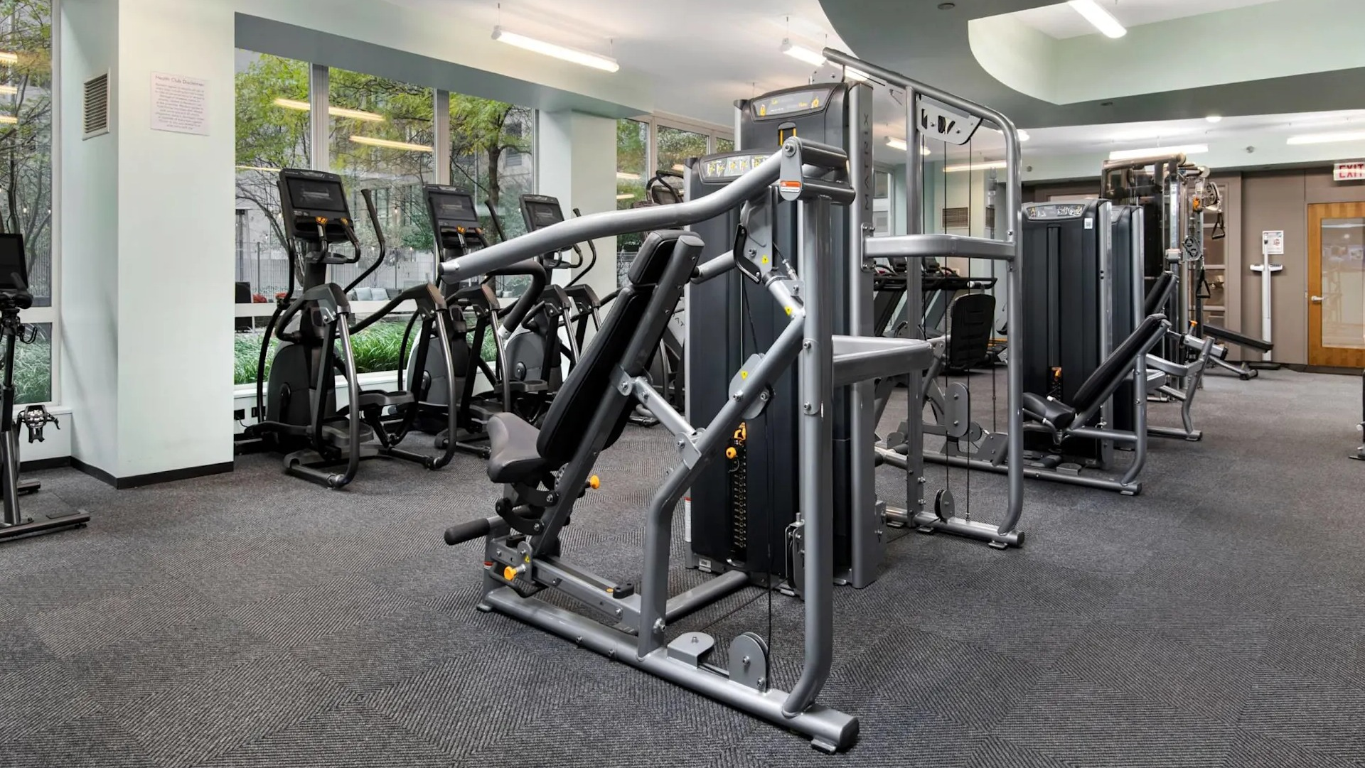 Resident fitness center at 215 West apartments in Chicago with strength machines, cardio equipment, and large windows overlooking landscaped grounds