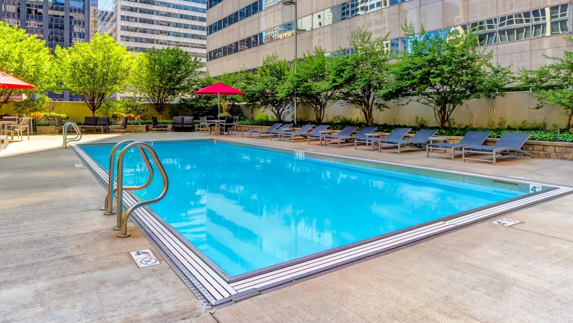 Outdoor swimming pool at 215 West apartments in Chicago, surrounded by lounge chairs, shade umbrellas, and city skyline views for relaxed summer days