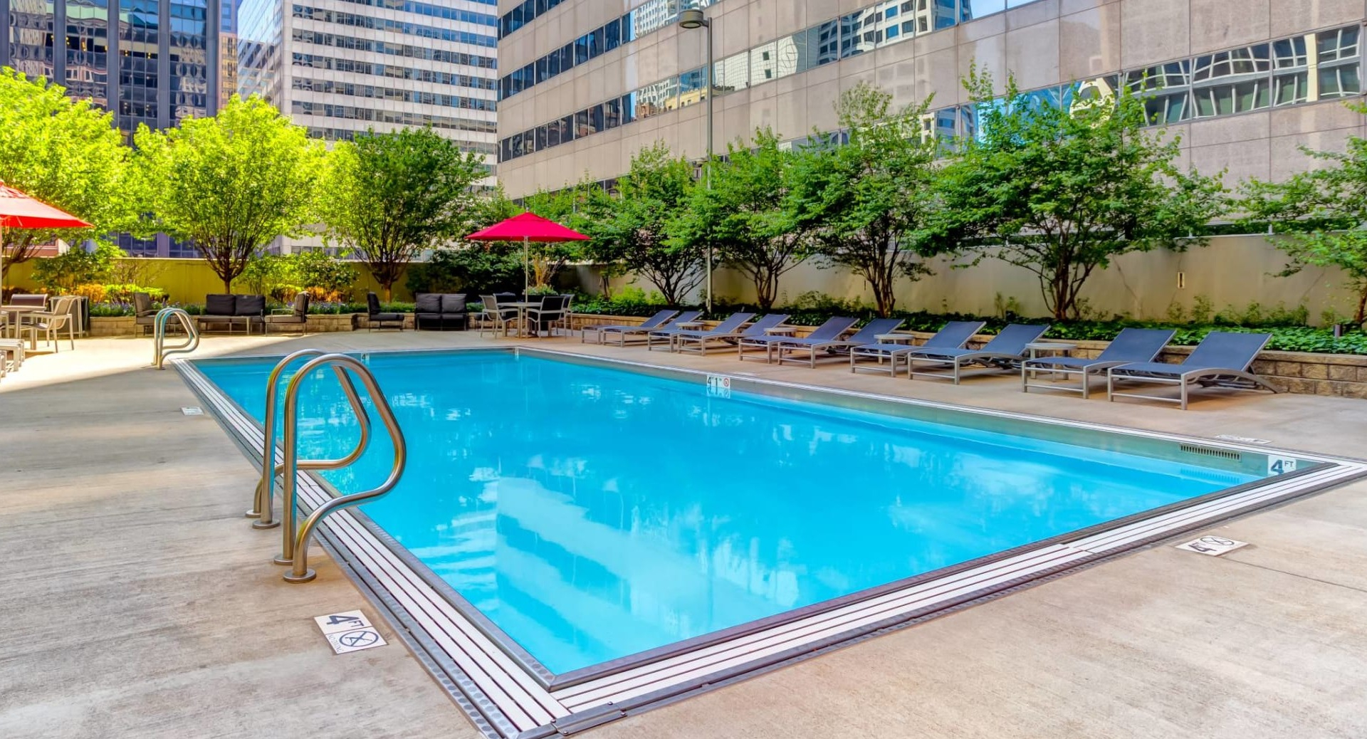 Outdoor swimming pool at 215 West apartments in Chicago, surrounded by lounge chairs, shade umbrellas, and city skyline views for relaxed summer days