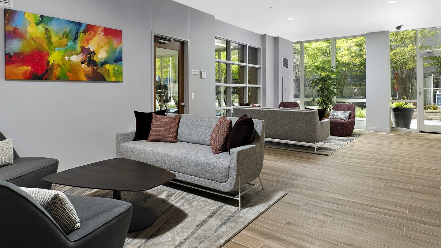Bright resident lounge at 215 West apartments in Chicago offering cozy sofas, accent chairs, art, and floor-to-ceiling windows to the courtyard