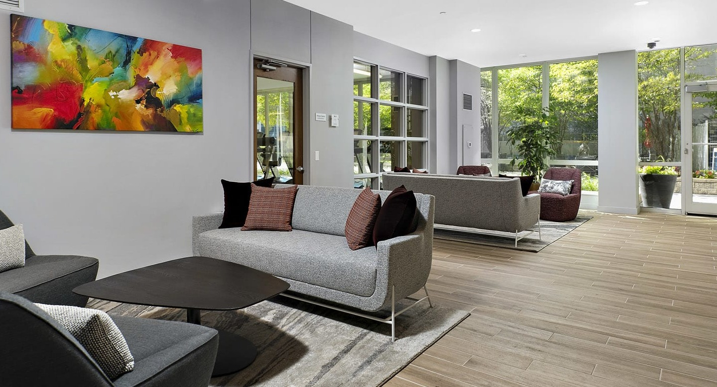 Bright resident lounge at 215 West apartments in Chicago offering cozy sofas, accent chairs, art, and floor-to-ceiling windows to the courtyard