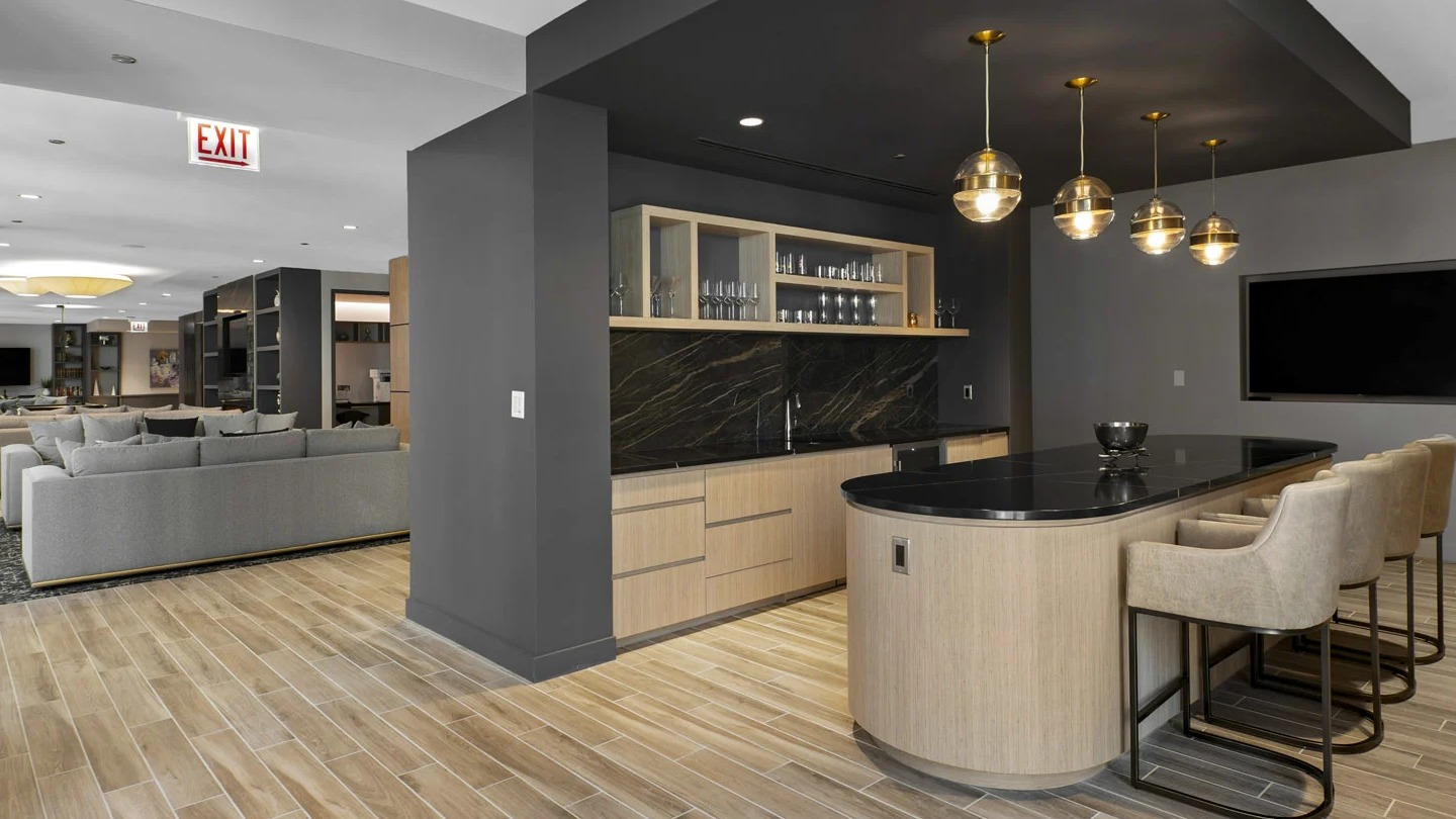 Social kitchen and lounge at 215 West in Chicago with a long island, built-in bar, open shelves, and views into the clubroom seating areas