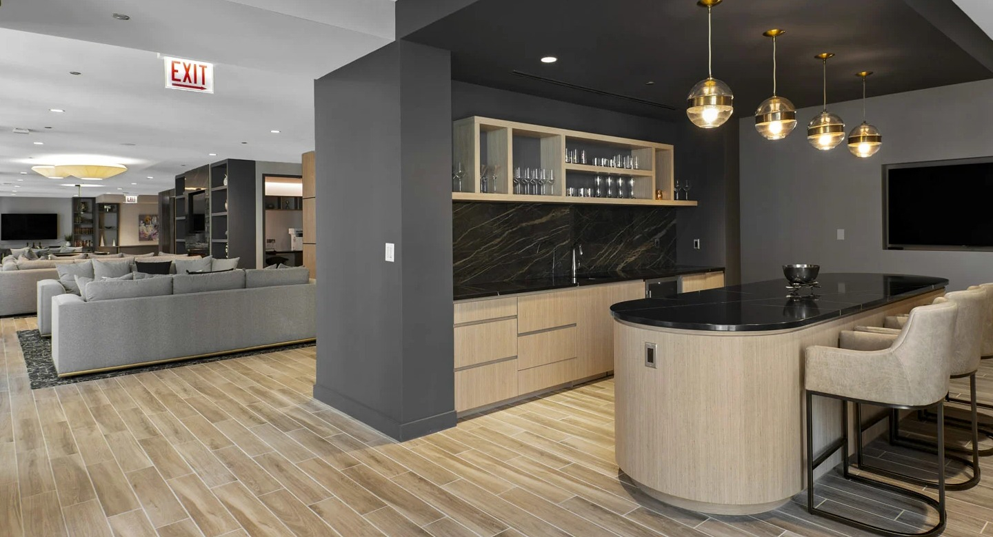 Social kitchen and lounge at 215 West in Chicago with a long island, built-in bar, open shelves, and views into the clubroom seating areas
